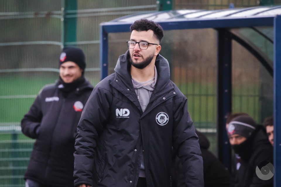 AR Elite Academy head coach at the dugout on a matchday, focused on the pitch